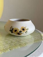 Front view of squat off-white vase with sunflower design