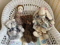 All four vintage stuffed toys displayed on wicker chair