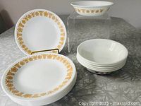 Stack of eight plates with floral border and stack of six bowls showing exterior pattern