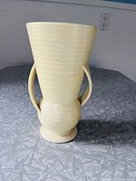 front view of pale yellow ribbed vase with curved handles