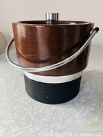 Front view of brown faux-leather ice bucket with chrome handle and black base