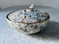 Covered bowl profile displaying splatter glaze and gold rim