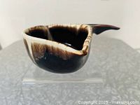 Profile of gravy boat showing brown drip glaze and one spout