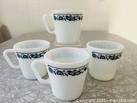 Four Pyrex Old Town Blue milk glass mugs on tabletop showing pattern and form
