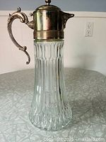 Full view of claret jug showing glass body and silver-plated handle and lid