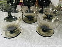 Group of smoky grey glass dessert bowls, close view of three front pieces highlighting color and foot details