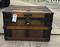 Front view of wood and metal steamer trunk showing latches and missing side handles