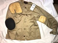 Full view of tan shooting jacket with leather pads, size tag visible