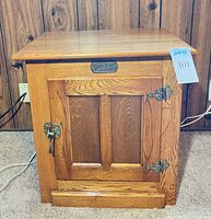 Front view of oak ice box style end table showing latch and hinges