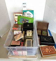 Plastic bin filled with numerous playing card decks, score pad, bridge accessories and boxes