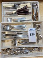 Flatware sorted in plastic tray showing forks, spoons, knives and spreaders