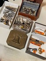 Grouped view of trays and cases with assorted cufflinks, tie bars, sterling and gold-filled pieces, Liberty Bell brass box