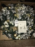 Tree components in box showing greenery, ribbons, ornaments and instruction sheet