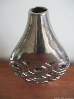 Front view of chrome-finish vase with geometric cutouts
