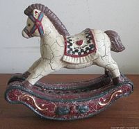 Side view of cream resin rocking horse on red rocker base