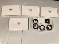 Four closed white boxes and one clear bag containing coiled black cables