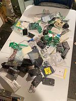 Table with multiple power adapters, circuit boards, sensors, component bags