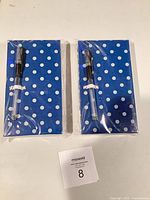 Front view of two sealed memo pads with pens