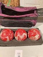 Three duckpin balls front view with carrying bag behind