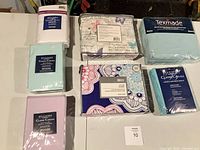 Group view of seven sealed queen bedding packages
