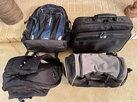 Four bags laid out: Canon camera backpack, laptop briefcase, small backpack, JanSport duffle