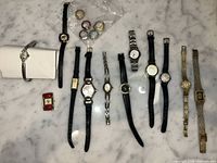 Group shot of all wristwatches, bezel rings and red square covers on marble surface