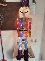 Full view of illuminated mesh nutcracker showing colors, lights on, and overall condition