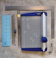 Overall lot showing trimmer, metal L-square, stainless ruler, EZ Angle ruler, cutting mat, clear right-angle ruler