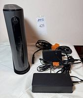 Front view of Motorola modem-router standing upright with two power adapters and cords