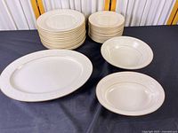 Stacked dinner and salad plates, platter, serving bowls displayed