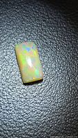 Rectangular opal showing play of color on textured background