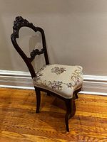 Full side view of carved wood chair showing frame, legs and upholstered seat