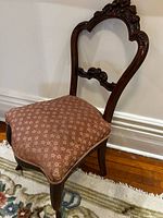 Full view of side chair showing carved back, seat upholstery, legs