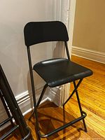 Single IKEA Franklin black metal bar stool against wall