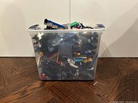 Clear bin filled with various LEGO pieces front view