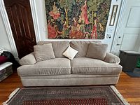 Front view of beige two-seat sofa with three pillows