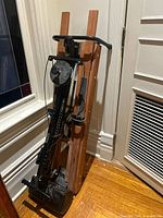 Machine folded upright showing full wooden frame, handlebars, and foot pads