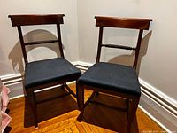 Front view of both matching wooden side chairs showing curved backs, rope-twist stretcher and upholstered pinstripe seats