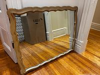 Full view of rectangular gilt-framed mirror leaning against wall