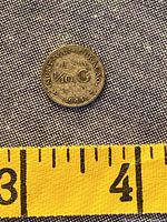 Reverse side of 1944 Curaçao 1/10 Gulden coin showing denomination and date next to ruler for scale