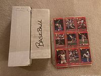 Closed white long box labelled Baseball next to stack of twelve red-border sleeved cards