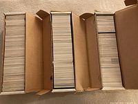 Four open long cardboard boxes filled with hockey cards
