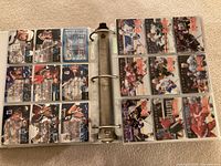 Open binder showing two pages of hockey trading cards, mix of front and back views