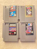 Four NES cartridges arranged in grid: Super Mario Bros./Duck Hunt, Lee Trevino’s Fighting Golf, Jeopardy, Major League Baseball