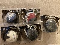 Front view of five sealed McDonald’s 2009 NHL goalie masks laid out showing player names