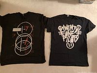 Two black Twenty One Pilots T-shirts laid flat
