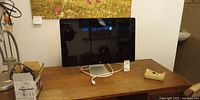 Front view of Apple 27-inch monitor on wooden desk with white cable
