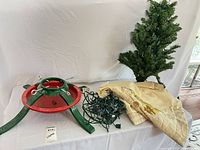 Artificial tree, stand, lights, skirt laid out on table