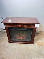 Front view of electric fireplace showing mantel, glass firebox with flames, and overall condition