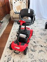 Angled front view of red eWheels mobility scooter with basket on rug